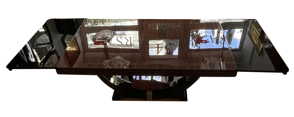 Art Deco dining table in Makassar ebony, accented with black lacquer and chrome—extendable—with gondola-style base; France, circa 1930. The beautifully grained tabletop, crafted from exquisite Makassar ebony, lends the table a distinctive character defined by fine craftsmanship and exclusivity.