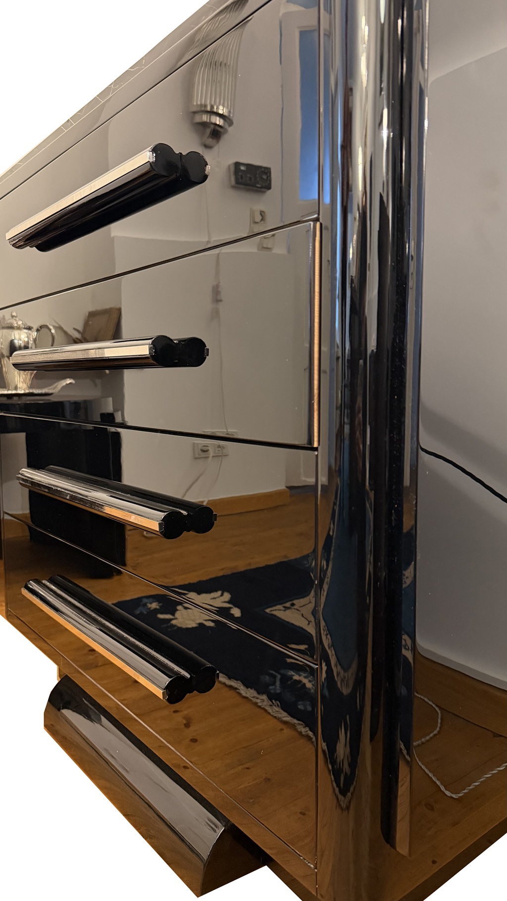 Angled front view of the four-drawer chest showing its glossy lacquer and stepped sides